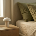 Lampada da comodino Kalakera in ceramica artigianale color burro. Il design a fungo con base opaca e paralume lucido si abbina a un arredamento da camera in stile minimalismo caldo e toni naturali.