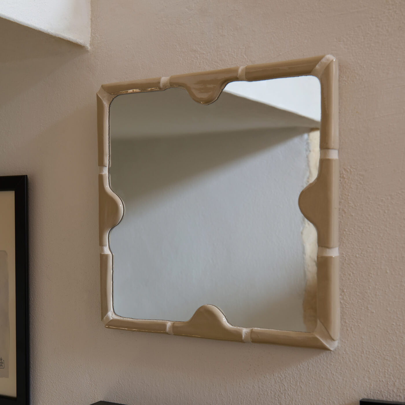 Specchio artigianale fatto a mano con cornice in ceramica materica color beige. Il design unico con dettagli a rilievo si adatta perfettamente a un arredamento mediterraneo moderno o boho-chic.