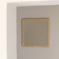 Specchio quadrato Kalakera con cornice in ceramica artigianale panna, illuminato da una luce radente che ne esalta i volumi. Un complemento di design materico per un arredamento minimalista e ricercato.