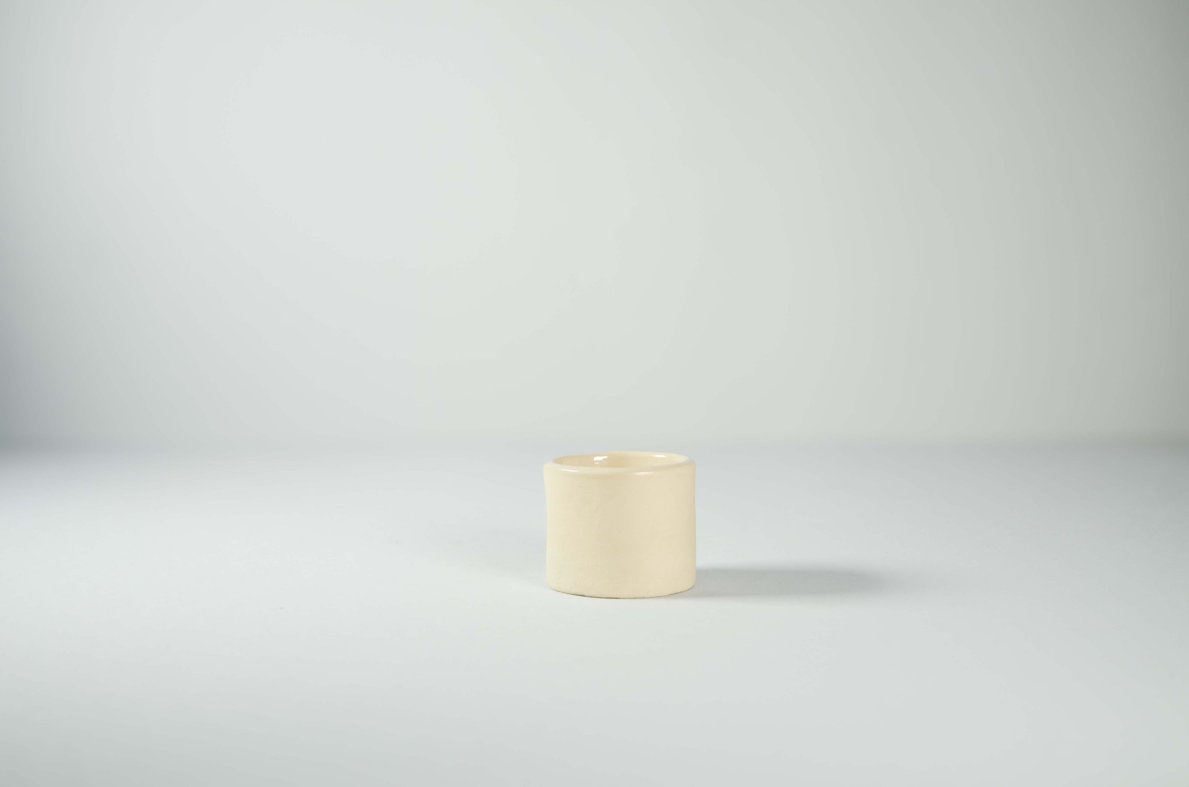 Tazzina da caffè espresso Kalakera in ceramica liscia color beige. Un design essenziale e scultoreo caratterizzato da linee pulite e volumi minimalisti, tipico dell'artigianato artistico contemporaneo.