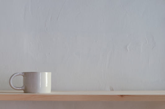 Nella foto appare una tazza è in ceramica fatta a mano, di colore bianco, e con il manico.
