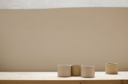 quattro tazzine del caffè fatte a mano in ceramica, due sono bianche e due sono beige