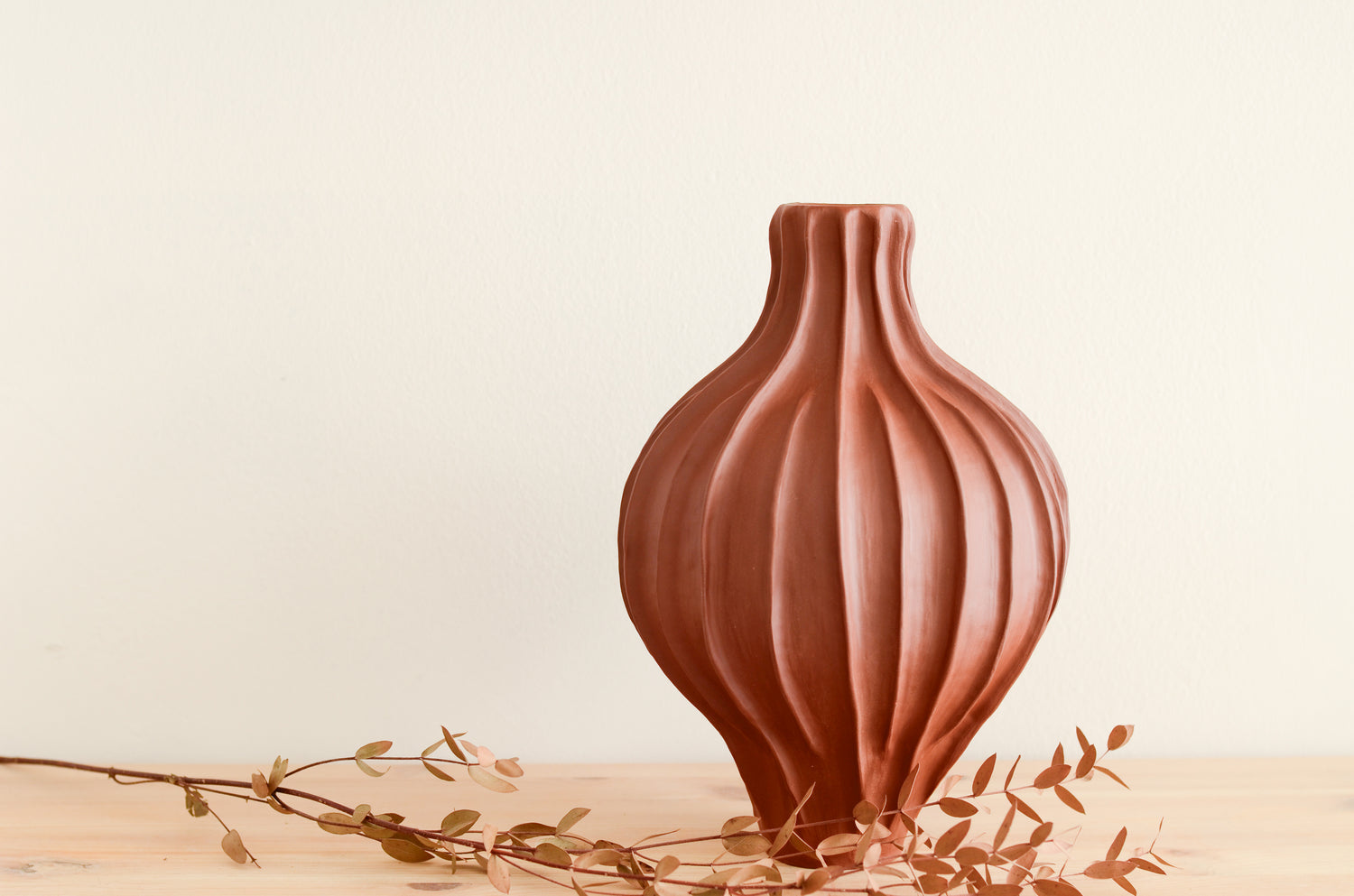 Vaso di ceramica fatto a mano di colore marrone - rossiccio. la forma è morbida, panciuta e ha una decorazione che ricorda delle creste.